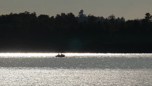 Silhouette of fishing boat at sunset. Sparkling reflections on lake. Ontario. HD.