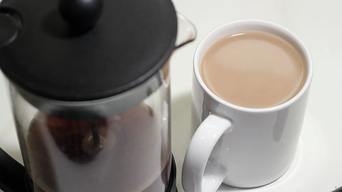 Adding sugar to milky cup of coffee. Mug in focus. HD video.