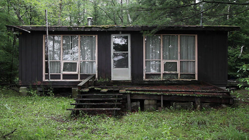 Old and abandoned cottage in the woods. Sound of rain falling. HD video.