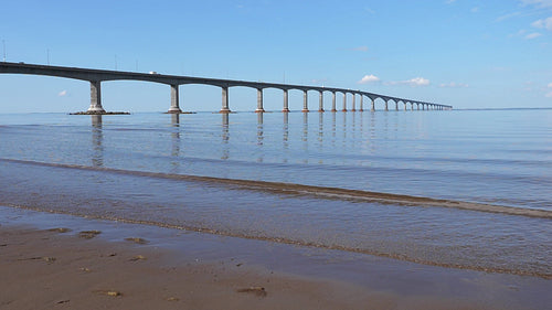 Slow motion sunlit waves with Confederation bridge. New Brunswick, Canada. HD.