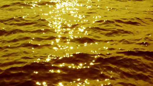 Slow motion surface of waves in blue lake. Defocused sun highlights. Gold tint. HD.