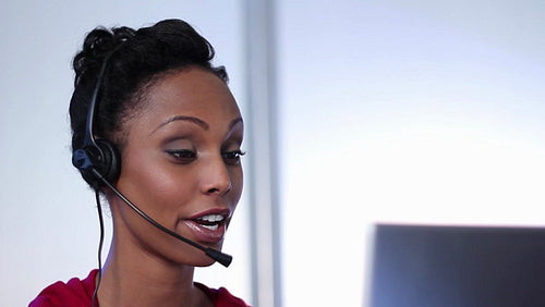 Call center. Attractive young black woman helps someone on the phone. HD.