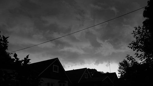 Scary looking storm clouds move over suburban neighbourhood. Black and white. HD.