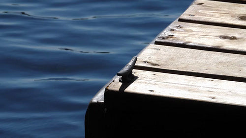 Detail of wooden dock and cleat. Slow motion lake with highlights. HD.