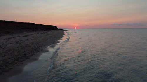 Sunset drone flight over waves by seashore. PEI, Canada. 4K.