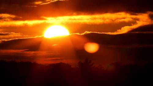 Dramatic orange sunset with sun moving behind clouds. Time lapse. HD.