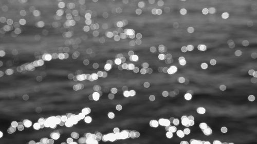 Slo mo defocused highlights on sunlit lake water. B&W. Lake Ontario, Canada. HD stock video.