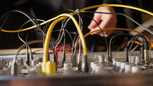 Electronic musician works on a live mix. Modular synthesizer with cables. HD.