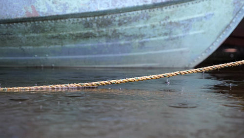 Detail of old yellow rope with rain falling. Defocused blue boat in bground. 4K.