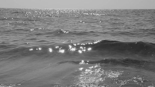 Slow motion tracking shot of sparkling wave cresting and breaking. Black & white. HD video.