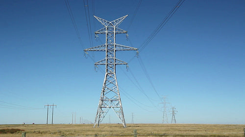 Big electrical pylons in the prairies. Traffic on horizon. Alberta, Canada. HD.