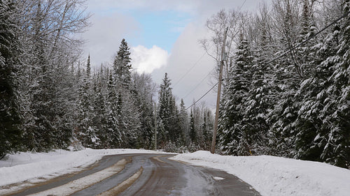 Winter road. Snowy road with snow covered trees and cloudy sky. Ontario. 4K.