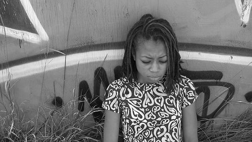 Defiant, sad girl smoking against a wall. Black and white. HD video.