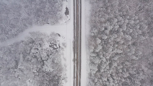 Drone following path of rural winter road. Flying in a snowstorm. Ontario, Canada. 4K.