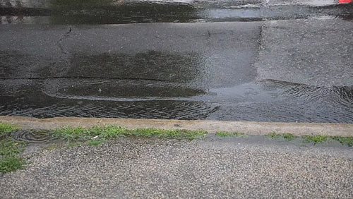 Slow motion shot of rain with roadside gutter and water flowing. Toronto. HD.