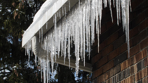 Frozen drainpipe and house gutter or eavestrough with icicles. Winter. 4K.