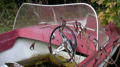 Abandoned red boat in forest dump. Closeup. HDV footage. HD.